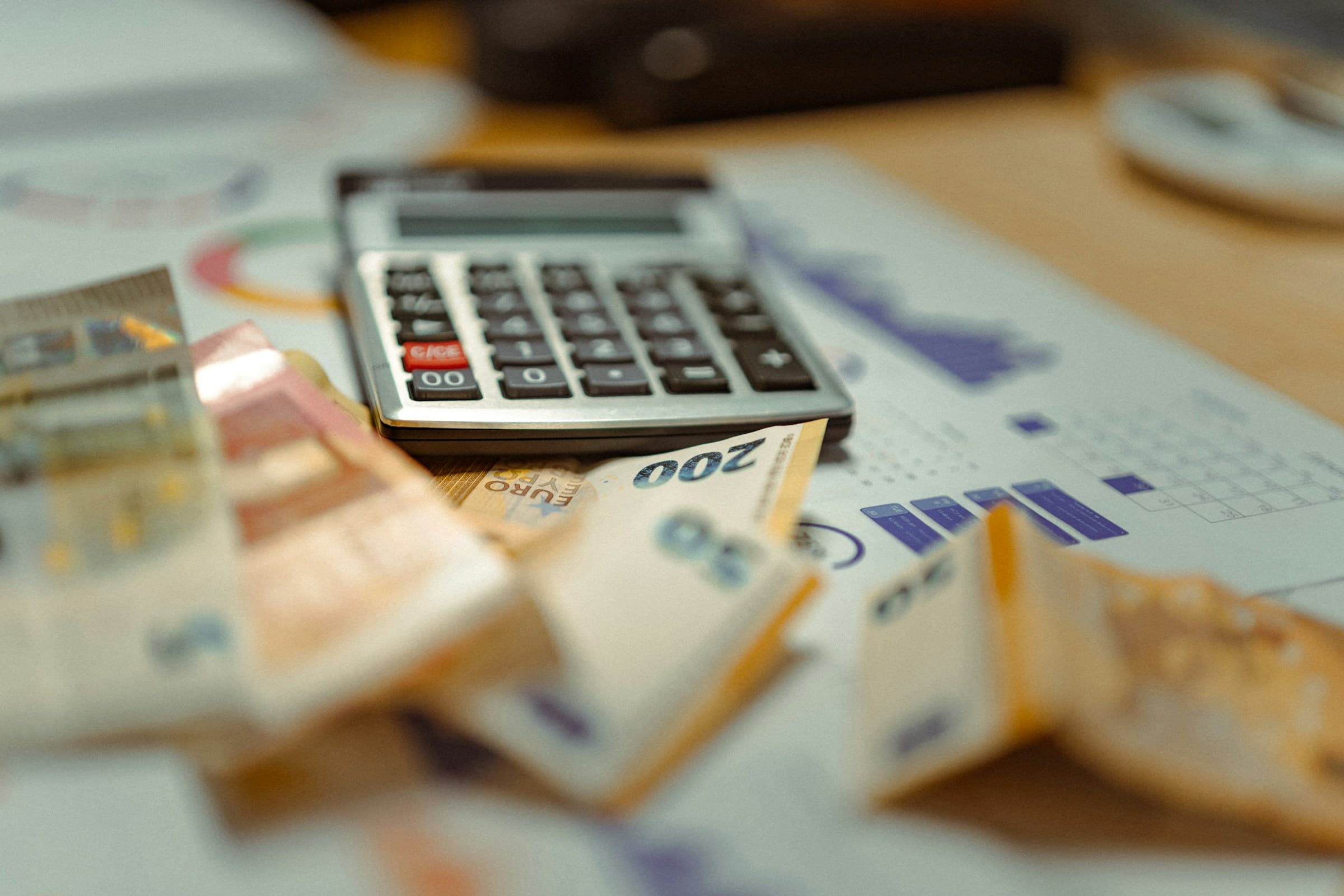 Calculator resting on a pile of money and financial papers